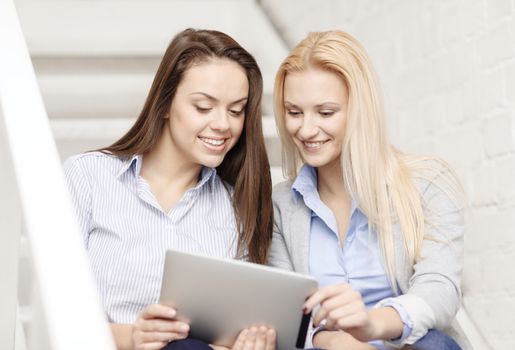 business, technology and startup concept - smiling creative team with tablet pc computer sitting on staircase