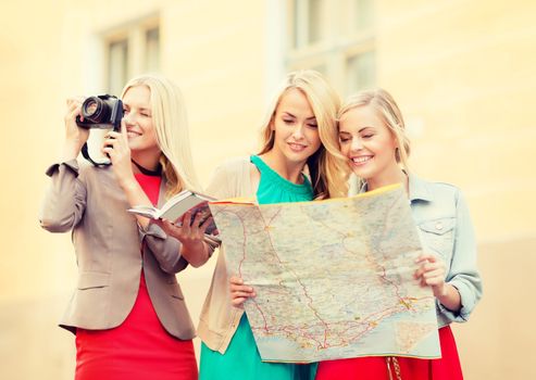 holidays and tourism concept - beautiful blonde women with tourist map and photo camera in the city