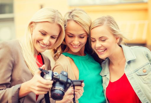 holidays, technology and tourism concept - beautiful blonde women with digital camera in the city