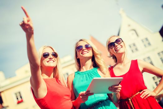 holidays and tourism concept - beautiful blonde girls toursits looking into tablet pc in the city