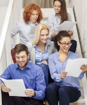 business, office and startup concept - smiling creative team with papers and take away coffee on staircase