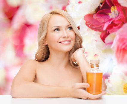 health and beauty concept - happy woman with oil bottle