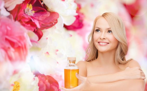health and beauty concept - happy woman with oil bottle