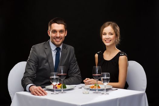 restaurant, couple and holiday concept - smiling couple eating main course with red wine at restaurant