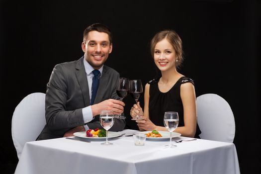 restaurant, couple and holiday concept - smiling couple eating main course with red wine at restaurant