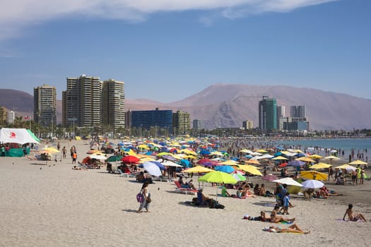 IQUIQUE, CHILE - JANUARY 23, 2015: Unidentified people enjoying the summer on the crowded Cavancha beach on January 23, 2015 in Iquique, Chile. Iquique is a popular beach town and free port city in Northern Chile.  