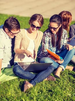 summer, internet, education, technlogy and campus concept - group of students or teenagers with laptop, notebooks and folders