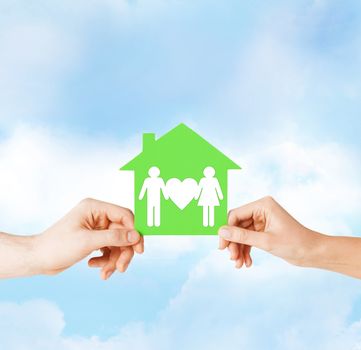 real estate and family home concept - isolated picture of male and female hands holding green paper house with family