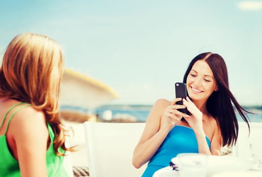 summer holidays, vacation and technology - girls taking photo with smartphone in cafe on the beach