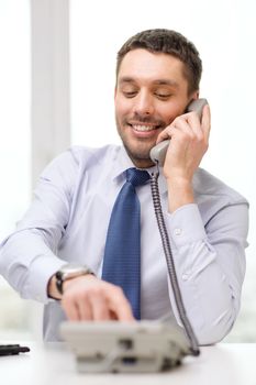 business, office and technology concept - smiling businessman with telephone dialing number at office