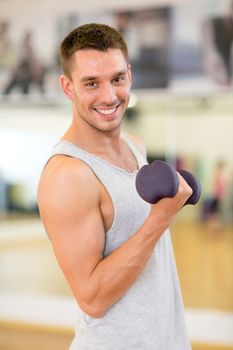 fitness, sport, training, gym and lifestyle concept - smiling man with dumbbell in gym