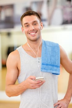 fitness, sport, training, gym, technology and lifestyle concept - young man with smartphone and towel in gym