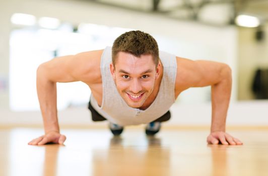 fitness, sport, training, gym and lifestyle concept - smiling man doing push-ups in the gym