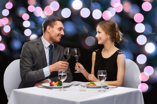 restaurant, couple and holiday concept - smiling couple eating main course with red wine at restaurant