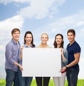 education and people concept - group of standing smiling students with white blank board