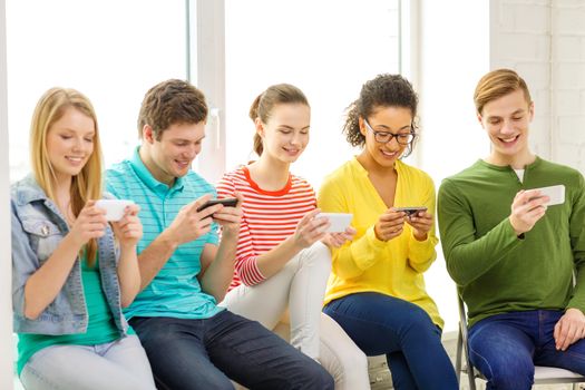 education, school and technology concept - smiling students with smartphone texting at school