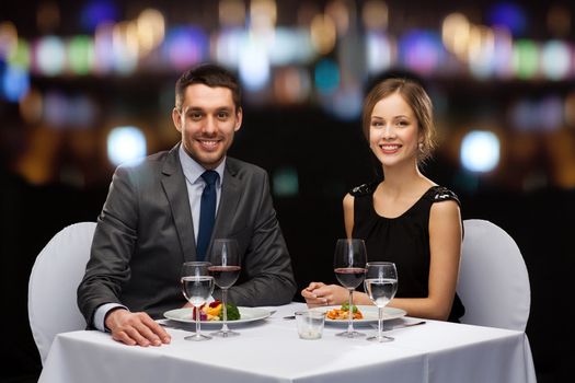 restaurant, couple and holiday concept - smiling couple eating main course with red wine at restaurant