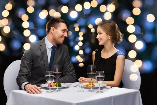 restaurant, couple and holiday concept - smiling couple eating main course with red wine at restaurant