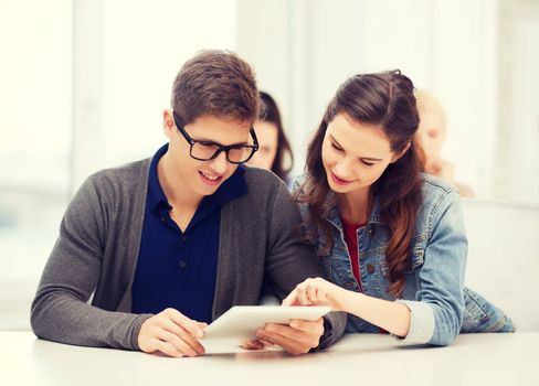 education, technology and internet - two smiling students looking at tablet pc in lecture at school