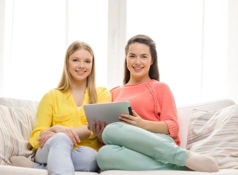 friendship, technology and internet concept - two smiling teenage girls with tablet pc computer at home