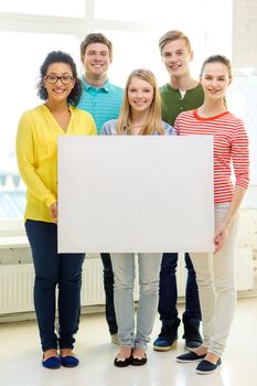 education, advertising and school concept - five smiling students with white blank board at school