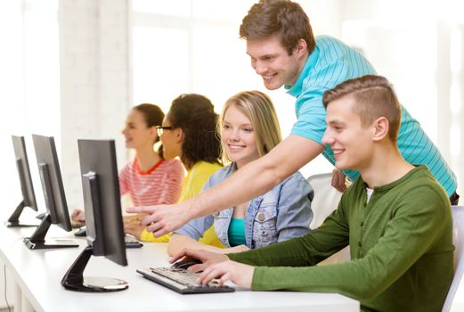 education, technology and school concept - smiling students in computer class at school