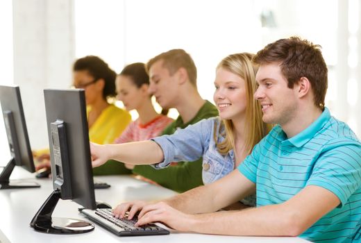 education, technology and school concept - smiling students in computer class at school