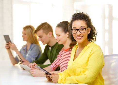 education, technology and internet concept - smiling female students with tablet pc computer and friends on the back at school