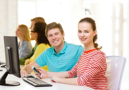 education, technology and school concept - smiling student with smartphone in computer class