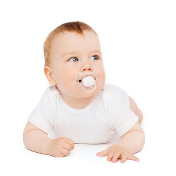 child and toddler concept - smiling baby lying on floor with dummy in mouth