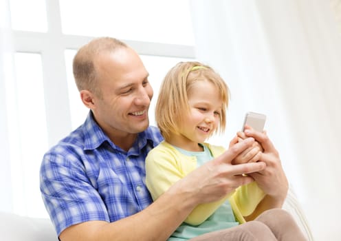 family, children, parenthood, technology and internet concept - happy father and daughter with smartphone at home