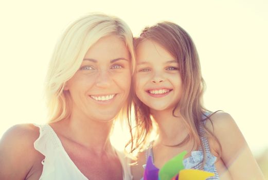 summer holidays, family, children and people concept - happy mother and child girl with pinwheel toy