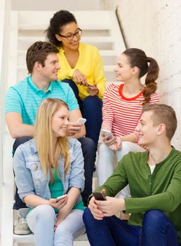 education, school and technology concept - smiling students with smartphone having discussion at school