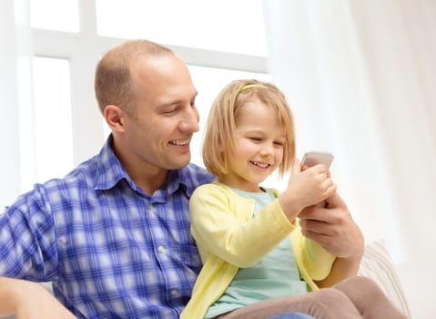 family, children, parenthood, technology and internet concept - happy father and daughter with smartphone at home