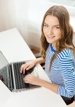 home, technology and internet concept - smiling teenage girl with laptop computer at home