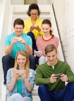 education, school and technology concept - smiling students with smartphone texting at school