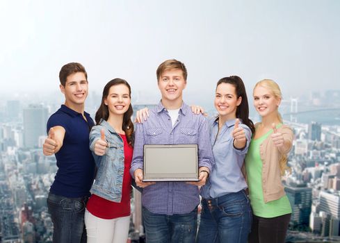 education, advertisement and new technology concept - smiling students with laptop computer blank screen showing thumbs up