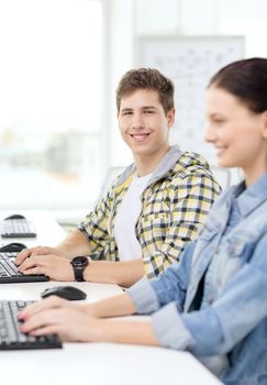 education, technology and school concept - smiling boy with girl in computer class at school