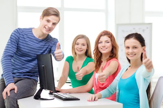 education, technology, school and people concept - group of smiling students showing thumbs up in computer class at school