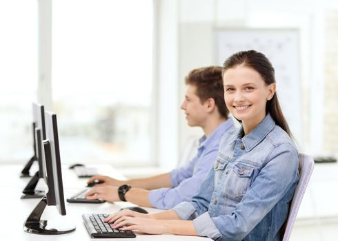 education, technology and school concept - two smiling students in computer class