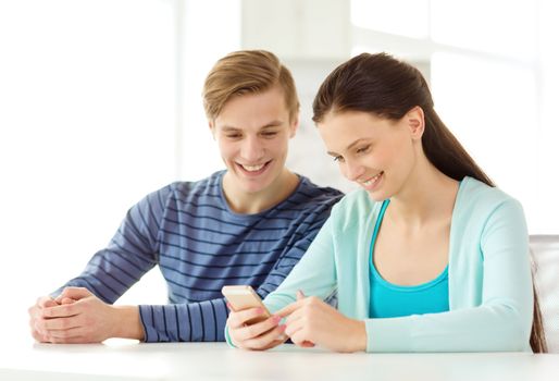 education, relationships and technology concept - two smiling students with smartphone at school