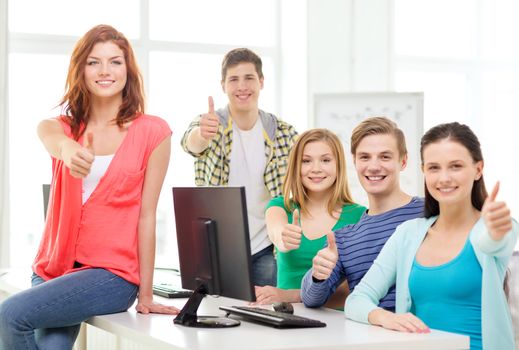 education, technology, school and people concept - group of smiling students showing thumbs up in computer class at school