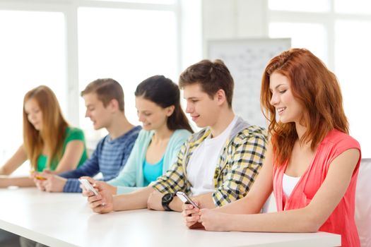 education, relationships and technology concept - group of smiling students with smartphones at school