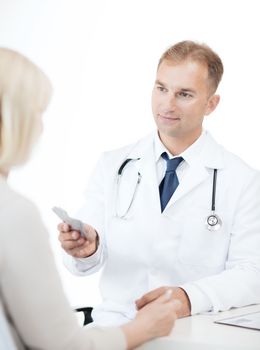 healthcare and medical concept - doctor giving tablets to patient in hospital