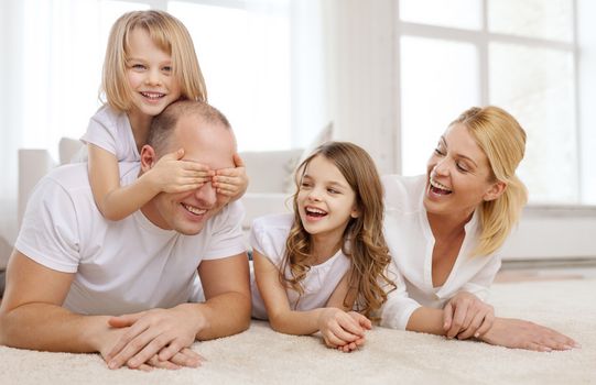 family, children and home concept - smiling family with and two little girls lying on floor at home and having fun