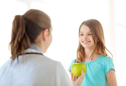 healthcare, child and medicine concept - female doctor giving an apple to smiling little girl