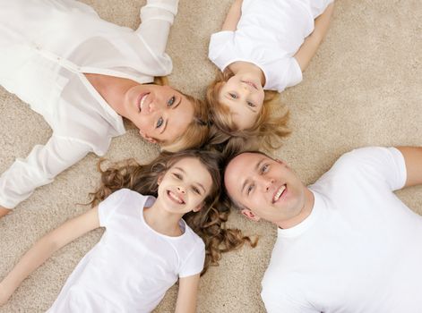 family, children and home concept - smiling family with and two little girls lying in circle on floor at home