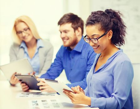 business, office and startup concept - smiling creative team with table pc computers and papers working in office