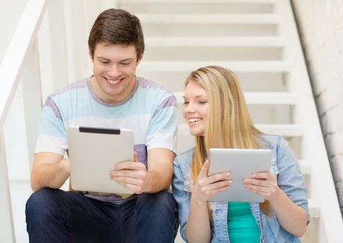 education and technology concept - smiling students with tablet pc computer sitting on staircase