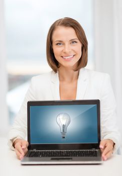 education, business, technology and internet concept - smiling woman with laptop computer in office